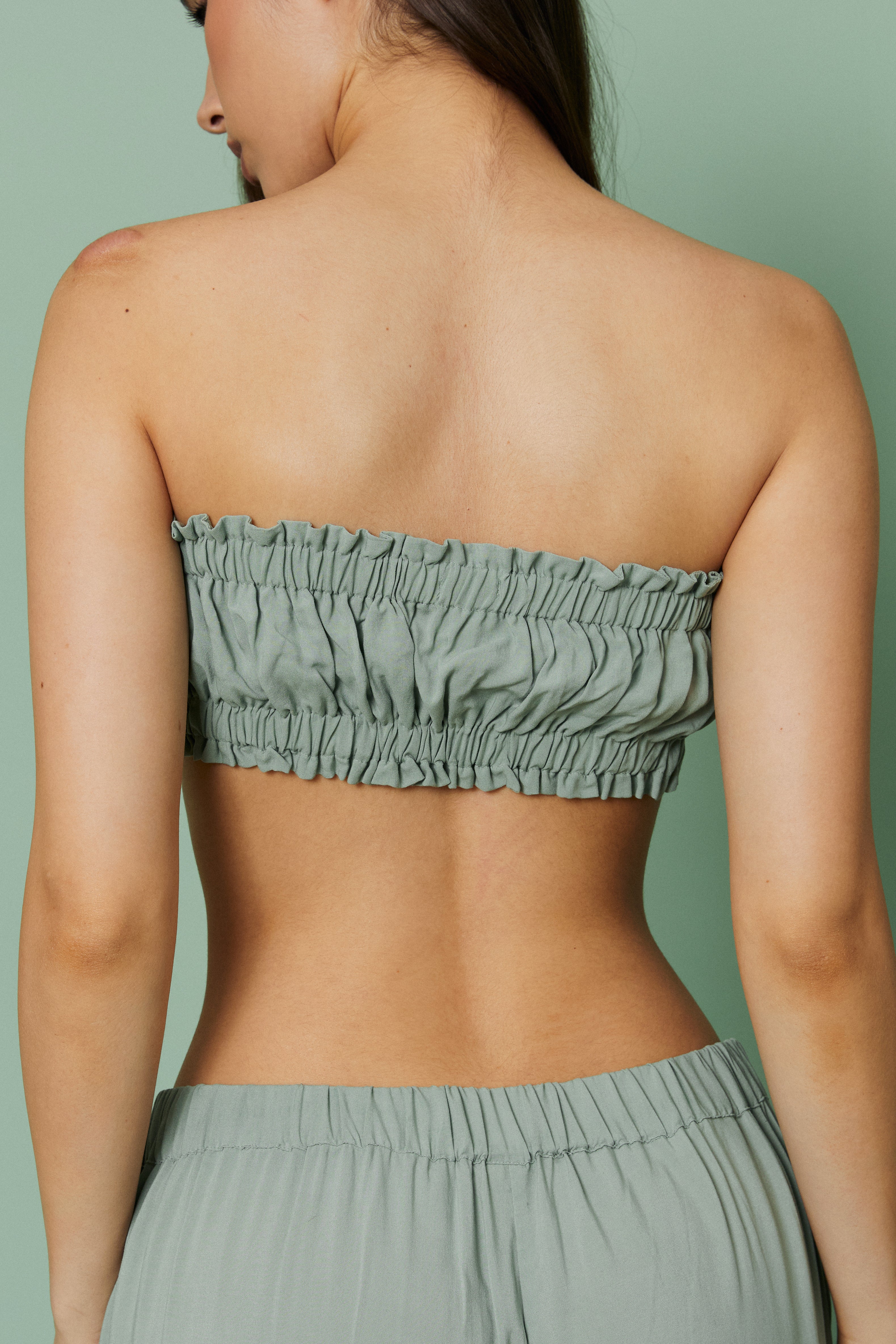 Back view of model in Azalea Green Voile Crop top, featuring ruched back detail and airy lightweight voile fabric.