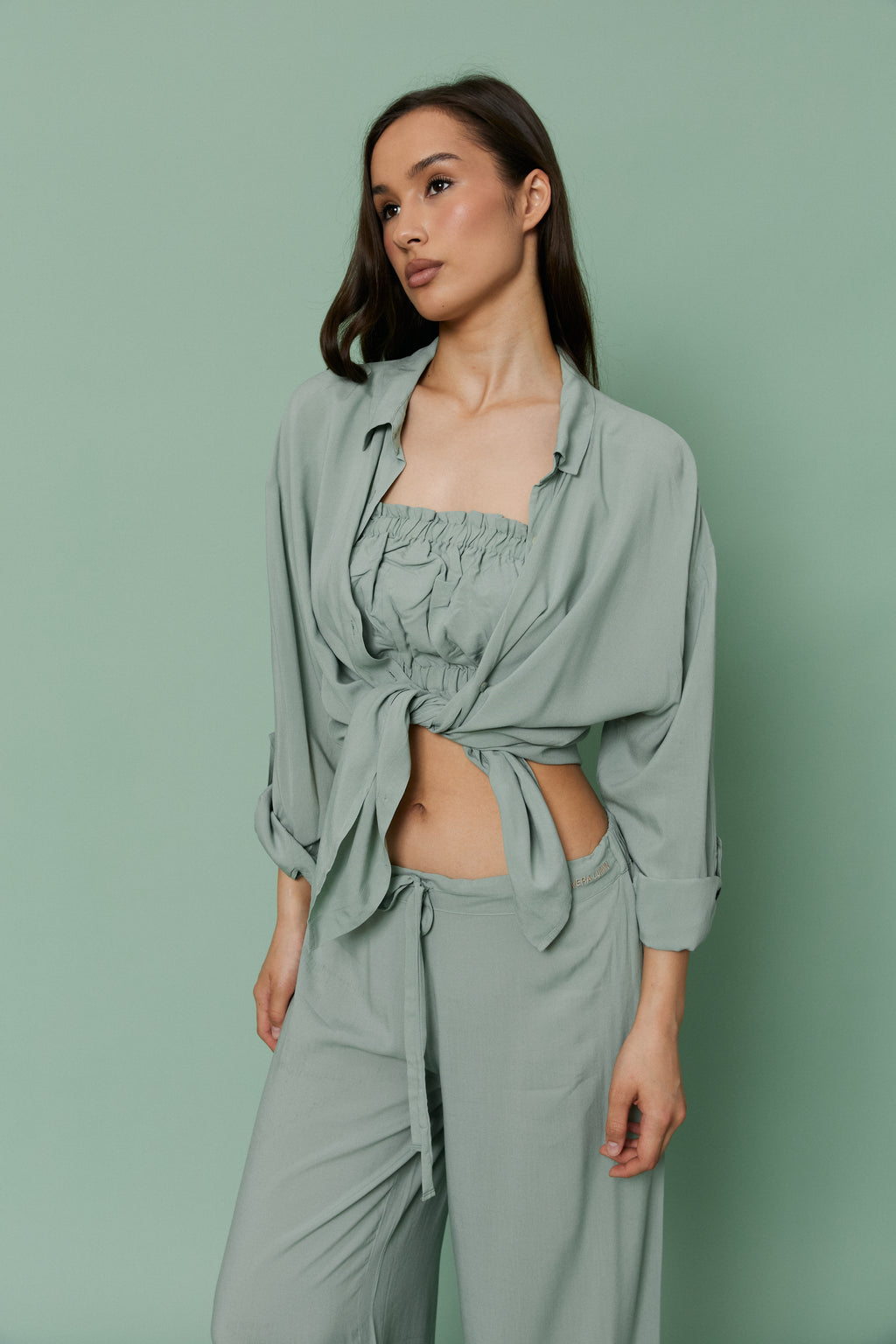 Full-length three-quarter front view of model wearing Azalea Green Voile Shirt tied at the waist over matching crop top and pants, showcasing lightweight sheer voile fabric.