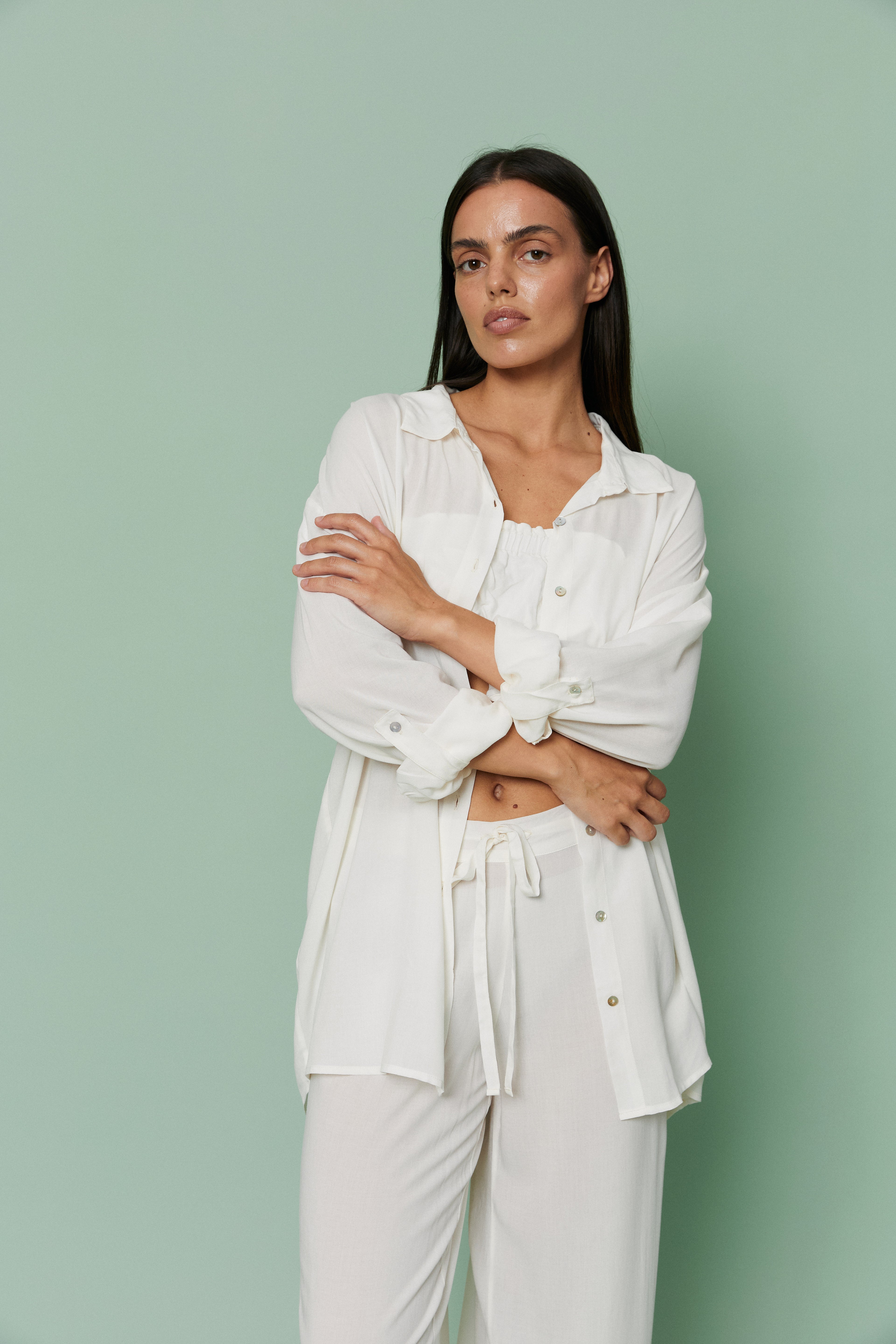 Front view of model wearing Azalea White Voile Shirt with arms crossed, featuring classic collar, button details and breathable voile fabric.