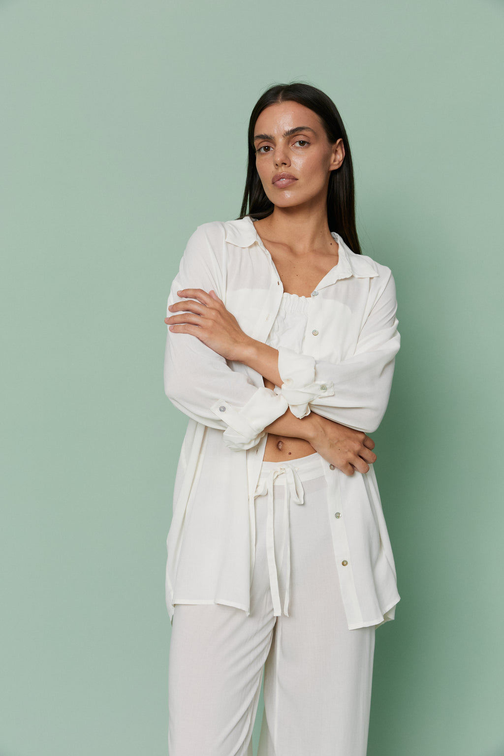 Front view of model wearing Azalea White Voile Shirt with arms crossed, featuring classic collar, button details and breathable voile fabric.