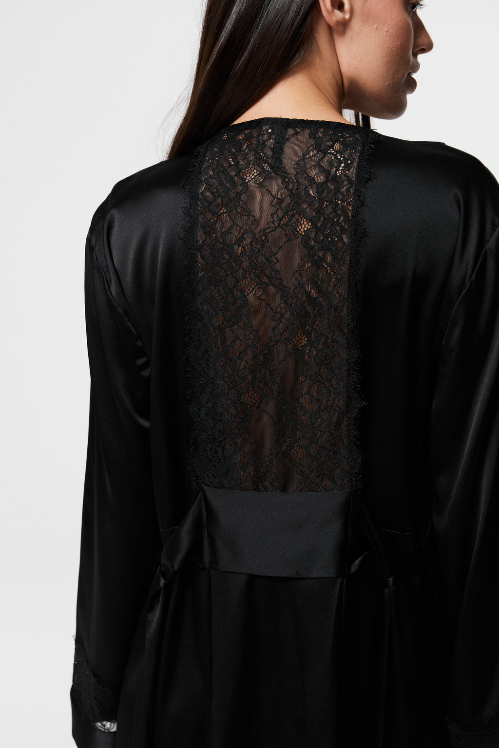 Model wearing Dicentra Black Silk Robe from the back, showcasing sheer black lace panel across upper back and silky fabric drape.